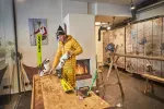 Person arbeitet an einem Holztisch in einer Werkstatt
