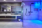 Modernes Badezimmer mit Glaskabine und blauer Beleuchtung