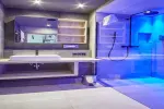 modernes Badezimmer mit Waschbecken, Regalen und blauer Beleuchtung