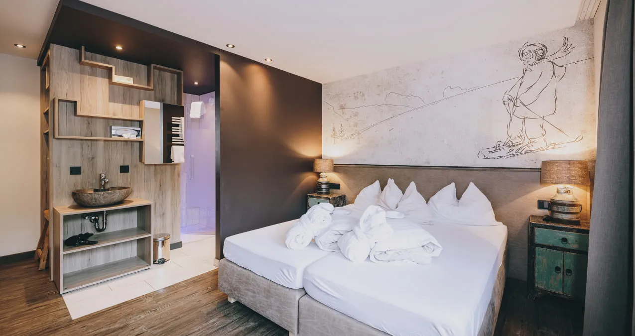 Modernes Zimmer mit zwei Betten, Holzmöbeln und Wandkunst.