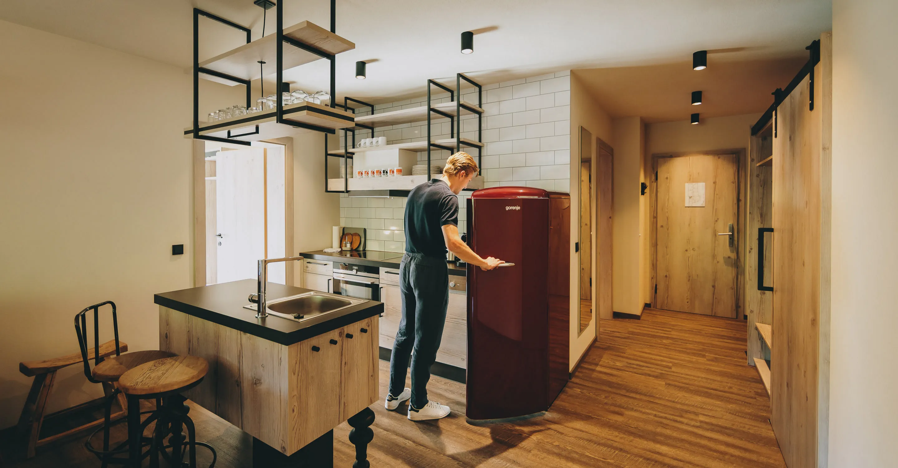 Moderne Küche mit Elektrogeräten und Holzdetails, Person öffnet Kühlschrank