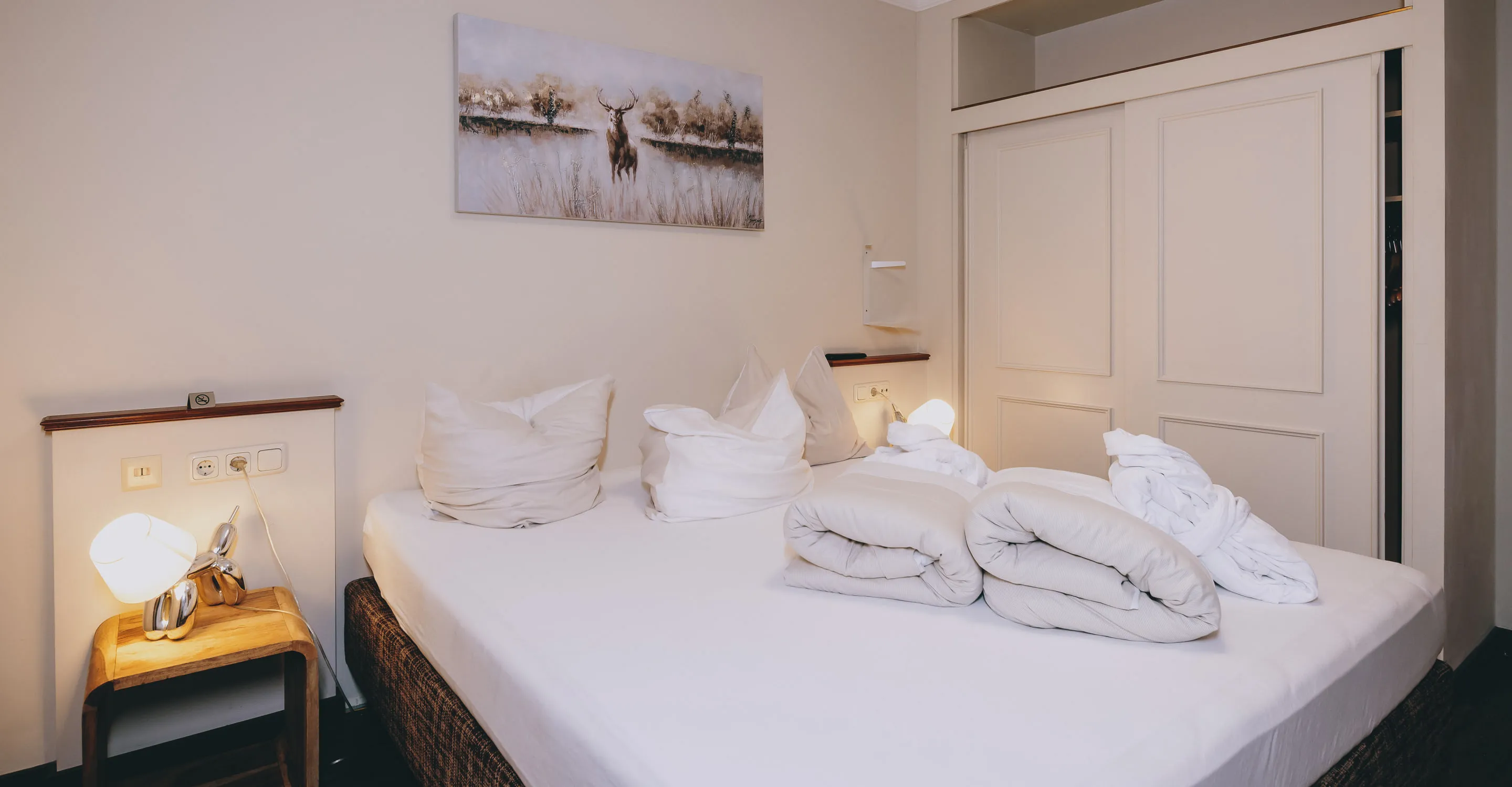 Schlafzimmer mit Bett, Kissen und Nachttischlampe, Dekoration an der Wand