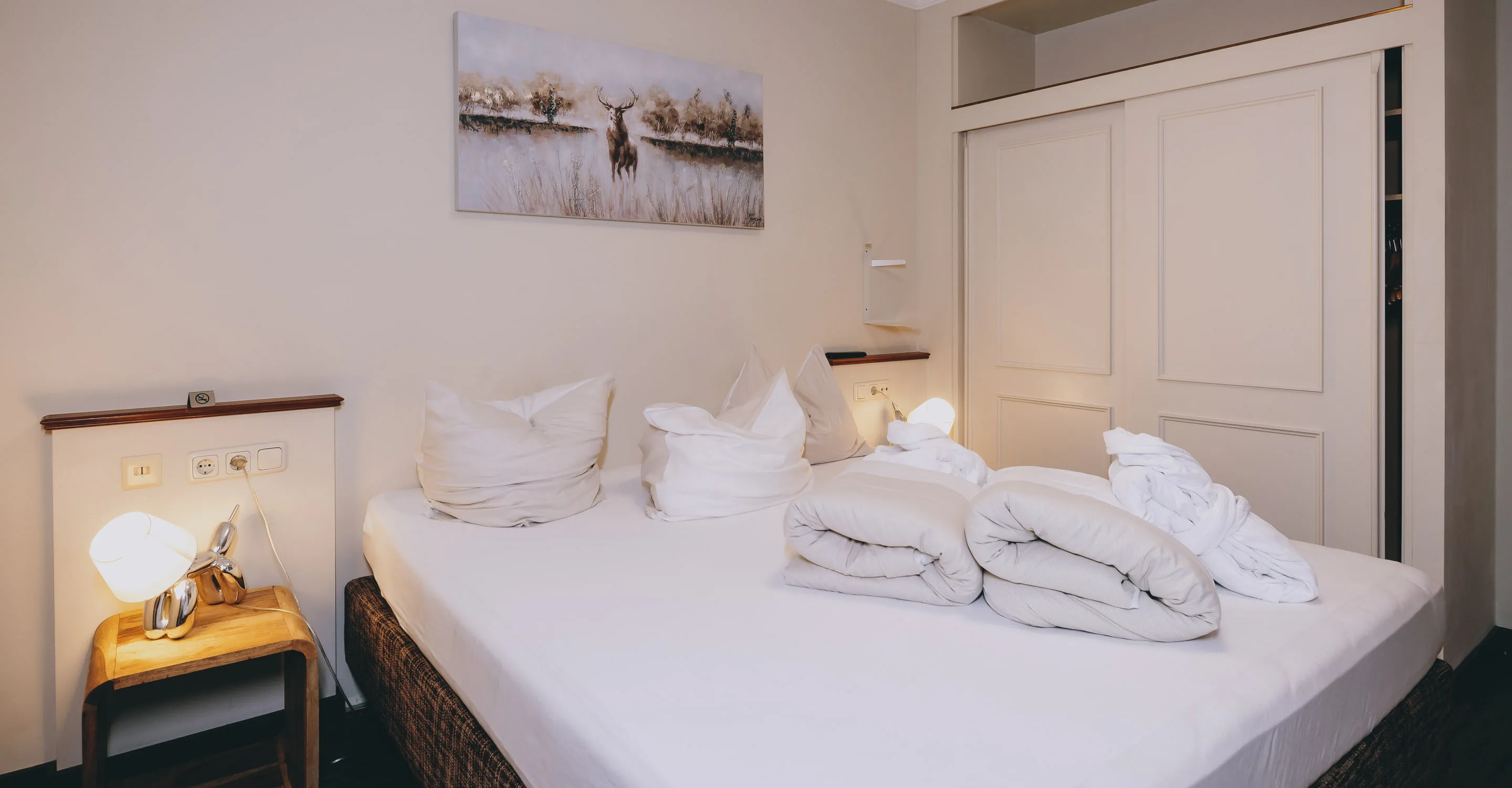 Zimmer mit Doppelbett, dekorierten Kissen und hellen Wänden