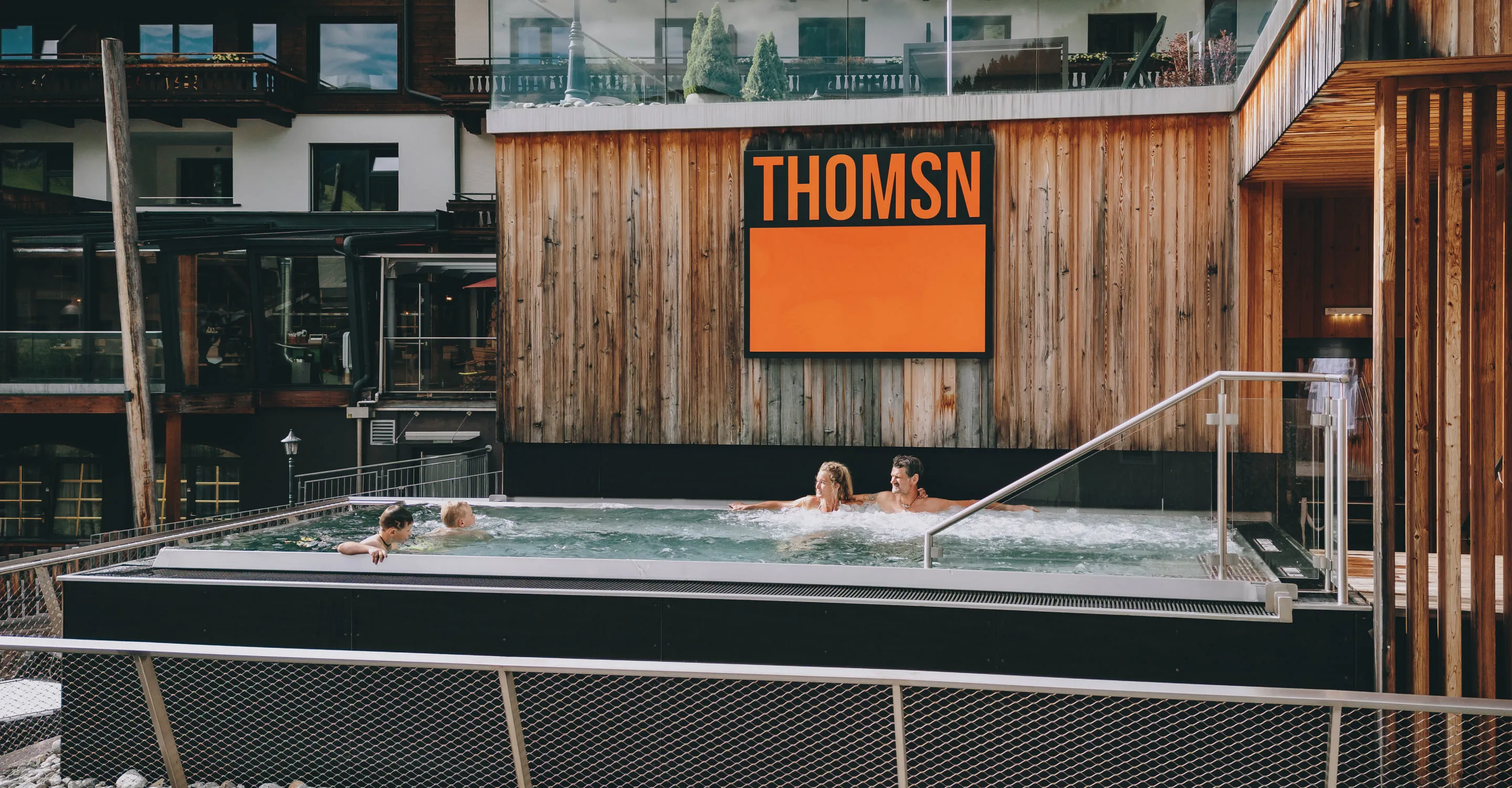 Wellnessbereich mit Schwimmenden im Außenbereich und Holzgebäude.