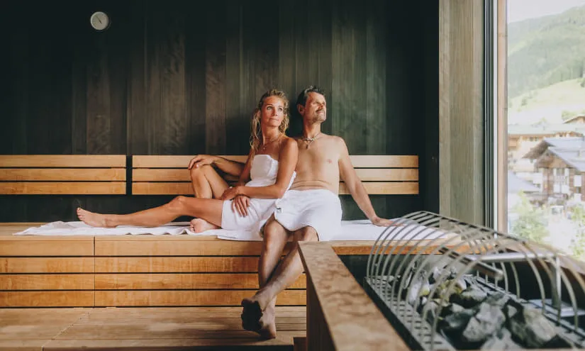 Pärchen in einer Sauna, entspannen auf Holzbank mit Blick nach draußen.