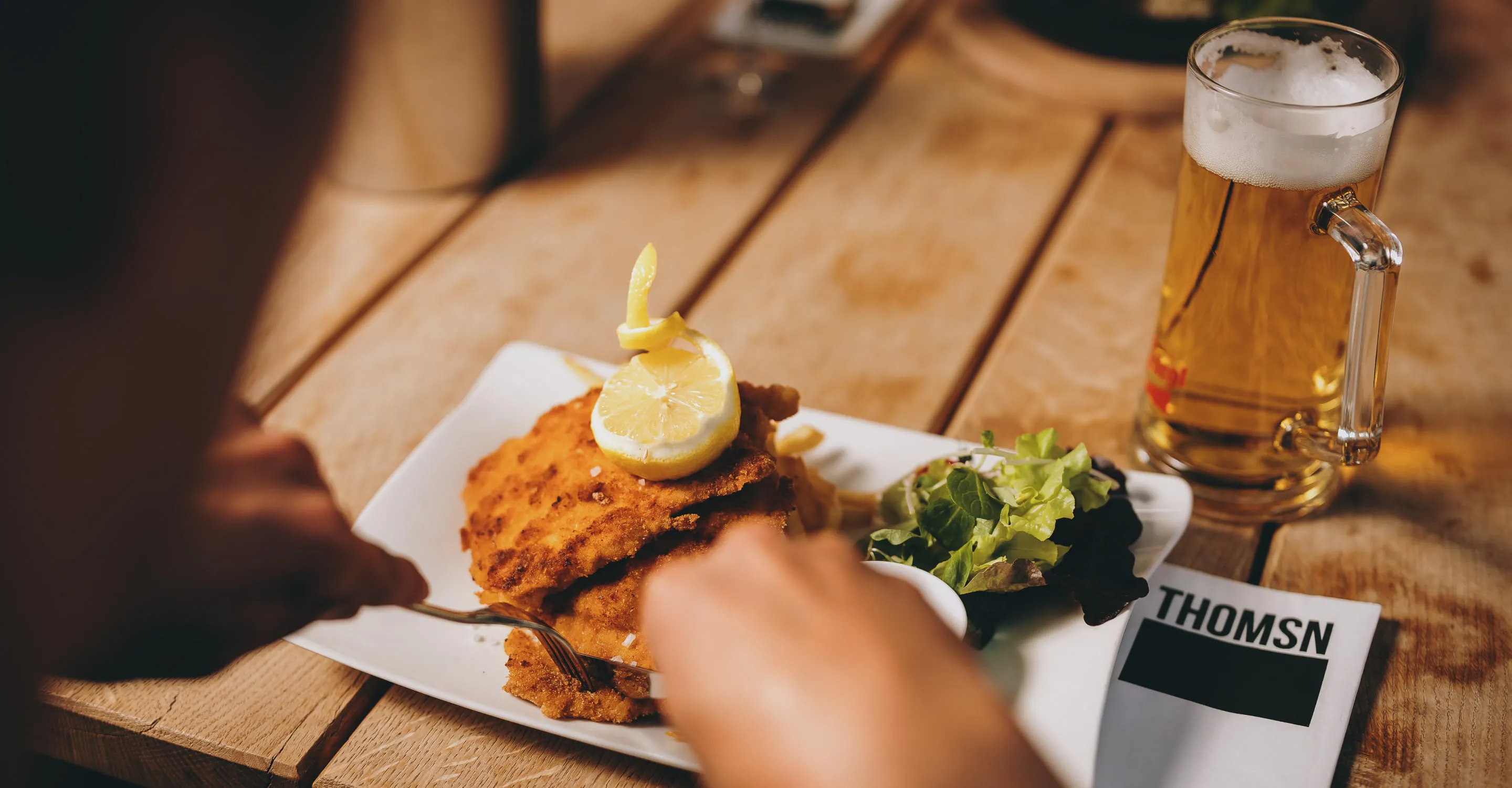 Teller mit Schnitzel, Salat und Bier in ThomSN, Hinterglemm.