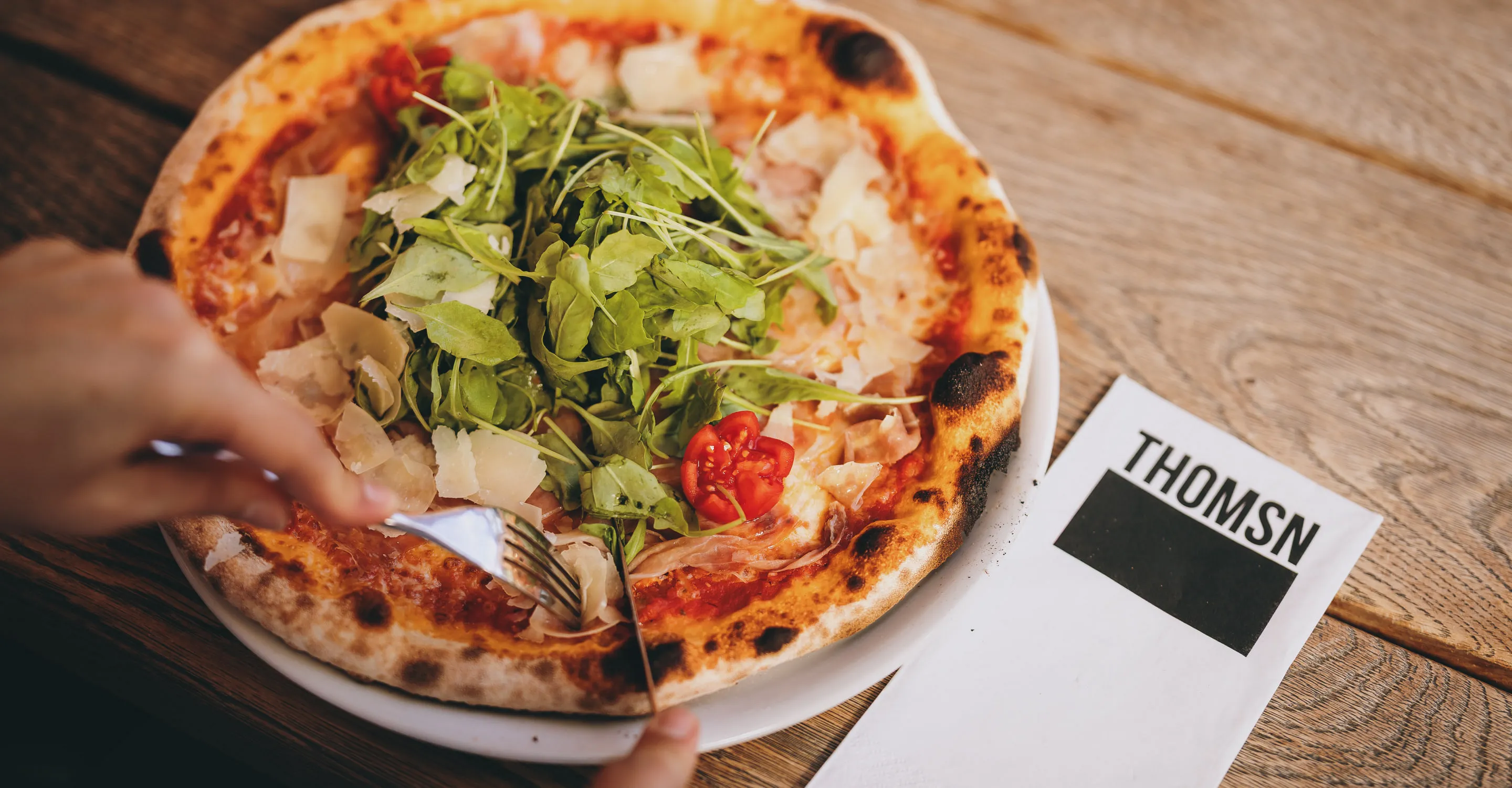 Pizza mit Salat auf einem Teller und einer Menükarten auf dem Tisch