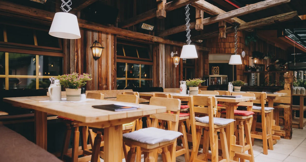 Gemütliches Restaurant mit Holztischen und Stühlen, Pflanzen und Lampen.
