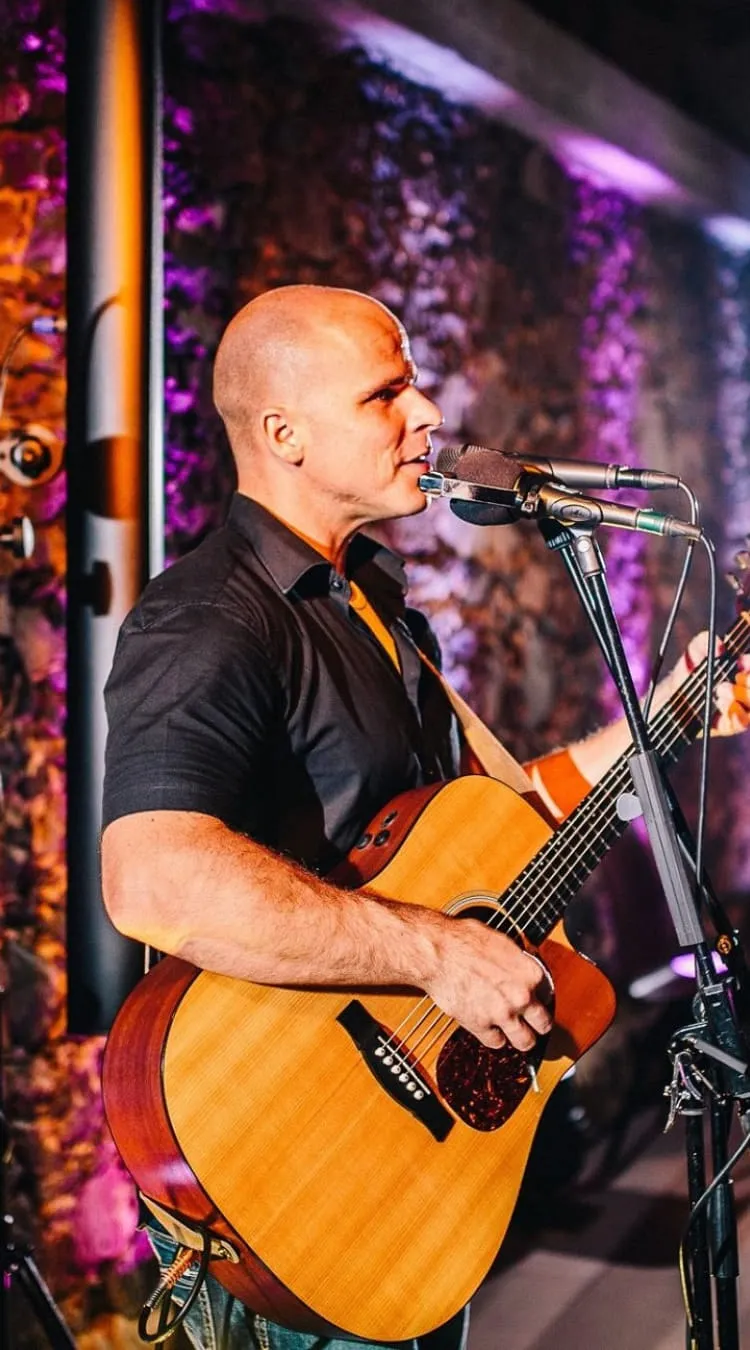 Mann spielt Gitarre auf der Bühne mit bunten Lichtern