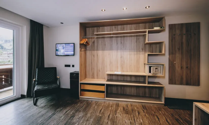 Heller Raum mit Holzregalen, Fernseher und Stuhl.