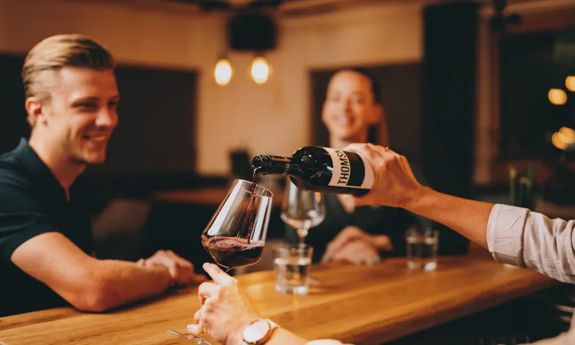 Gäste in der Thomsn-Hinterglemm-Bar, die Wein genießen und anstoßen.
