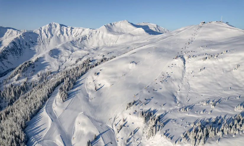 Schneebedeckte Berglandschaft mit Skipisten und Nadelwäldern