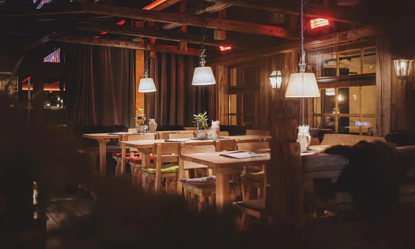 gemütliches Interieur eines Restaurants mit Holztischen und hängenden Lampen