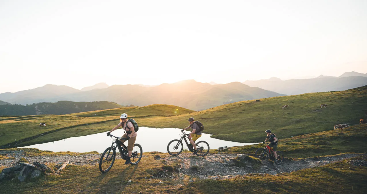 E-Mountain bikers riding in Saalbach-Hinterglemm at sunset