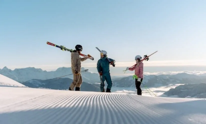 Drei Skifahrer mit Skiern auf einer schneebedeckten Piste im Skicircus Saalbach.