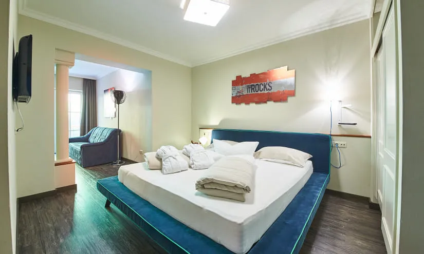 Helles Schlafzimmer mit blauer Bettwäsche und Fernseher