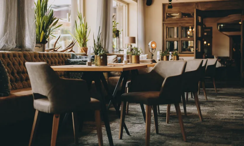 Gemütliches Restaurant mit Pflanzen und Tischen.