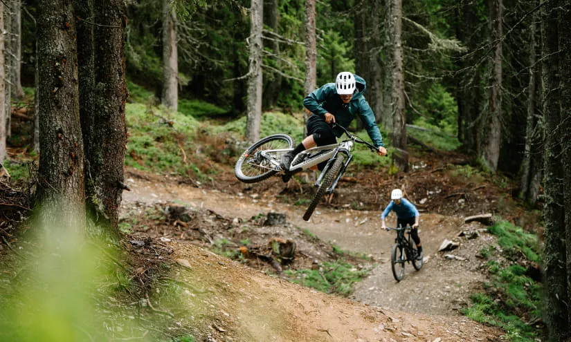 Biker springt über einen Trail im Wald.